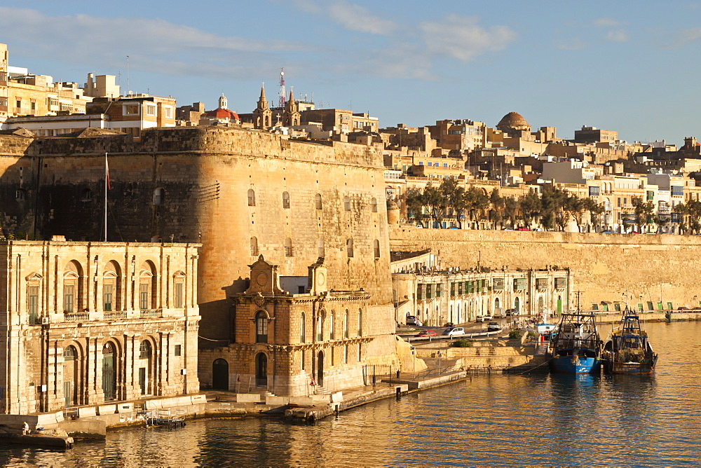 Fishing boats at the Barriera Wharf and Grand Harbour fortifications in the golden early morning, Valletta, Malta, Mediterranean, Europe