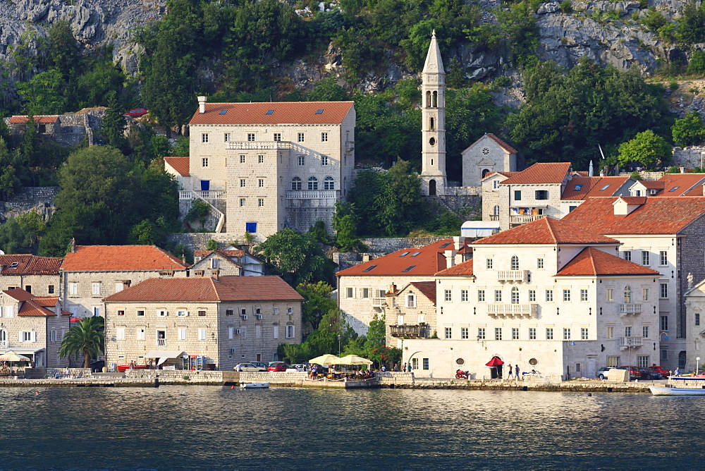 Church of Our Lady of the Rosary and a waterside restaurant lit by evening light, Perast, Bay of Kotor, UNESCO World Heritage Site, Montenegro, Europe