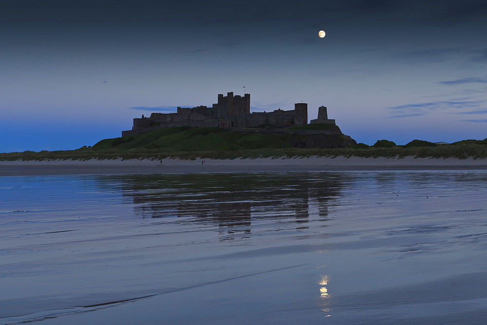 Bamburgh Castle under a full moon at dusk in summer, Bamburgh, Northumberland, England, United Kingdom, Europe