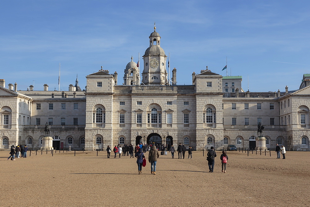 Tourists walk towards the arch of Horse Guards Parade under a winter's blue sky,  Whitehall, London, England, United Kingdom, Europe