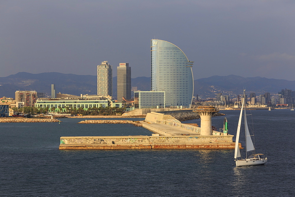 Yacht sails past La Barceloneta and the waterfront, Port Olimpic in distance, late afternoon, Barcelona, Catalonia, Spain, Europe