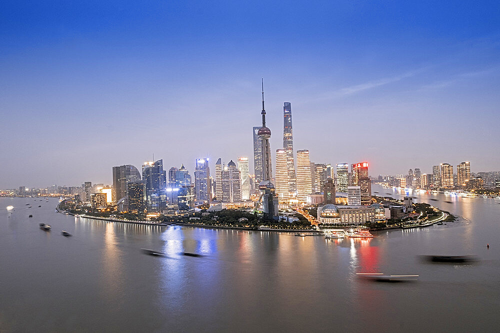 The illuminated skyline of Pudong district in Shanghai with the Huangpu River in the foreground, Shanghai, China, Asia