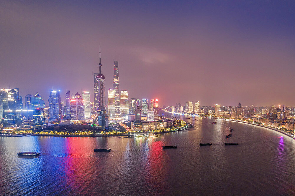 The illuminated skyline of Pudong district in Shanghai with the Huangpu River in the foreground, Shanghai, China, Asia