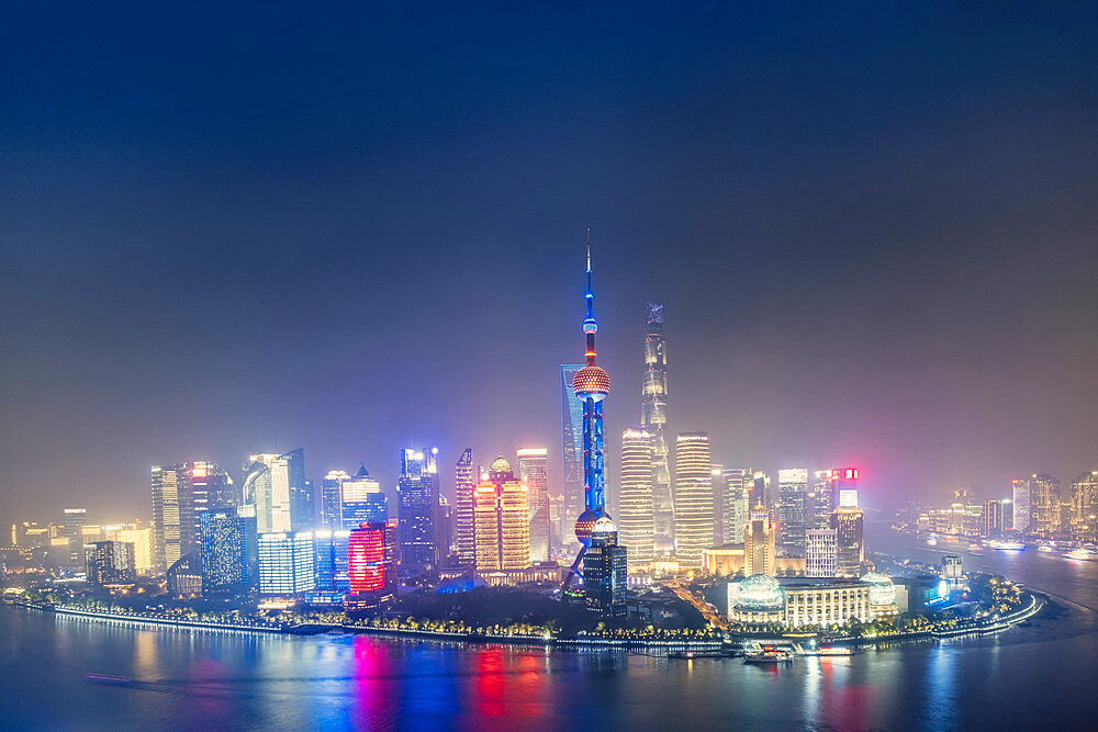 The illuminated skyline of Pudong district in Shanghai with the Huangpu River in the foreground, Shanghai, China, Asia