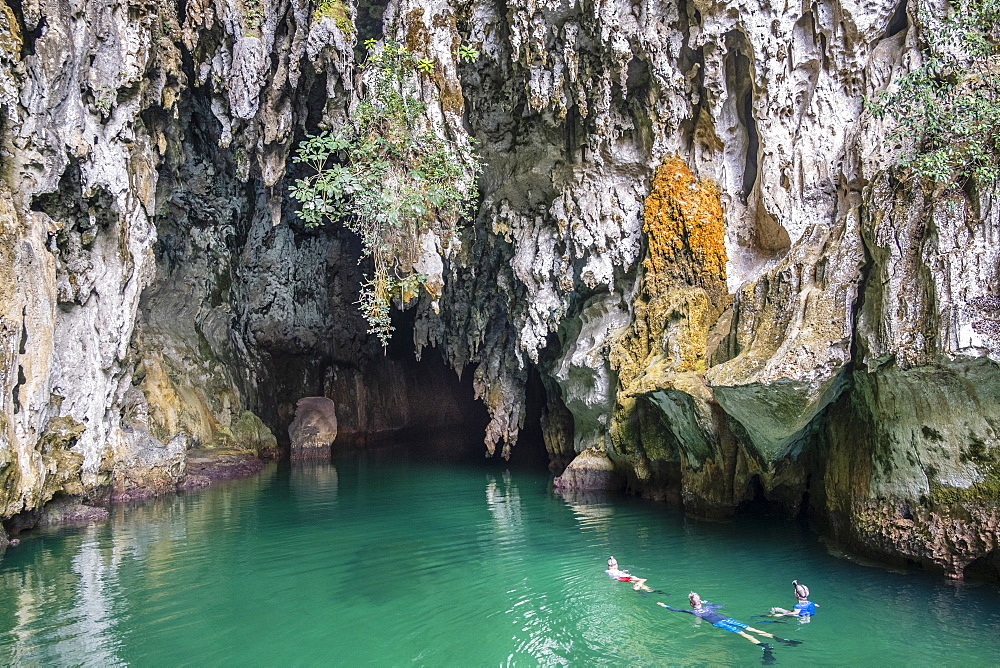 Snorkellers at the entrance to Tomolo (Goa Keramat) cave, Tomolo, Misool, West Papua, Spice Islands, Indonesia, Southeast Asia, Asia