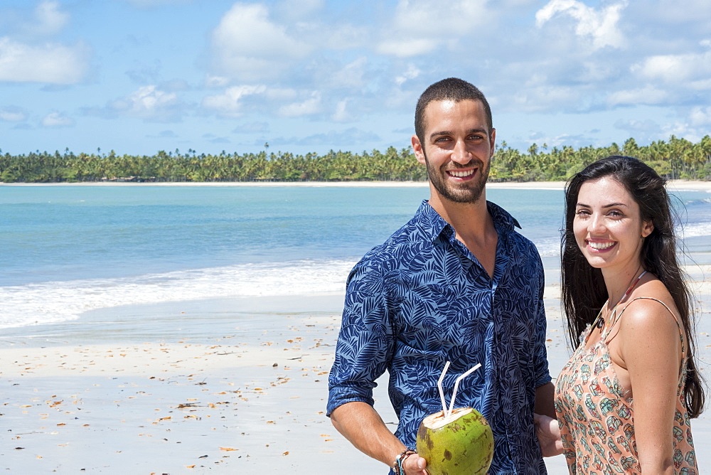 A good-looking Hispanic (Latin) couple smiling and standing together on a deserted beach, Brazil, South America