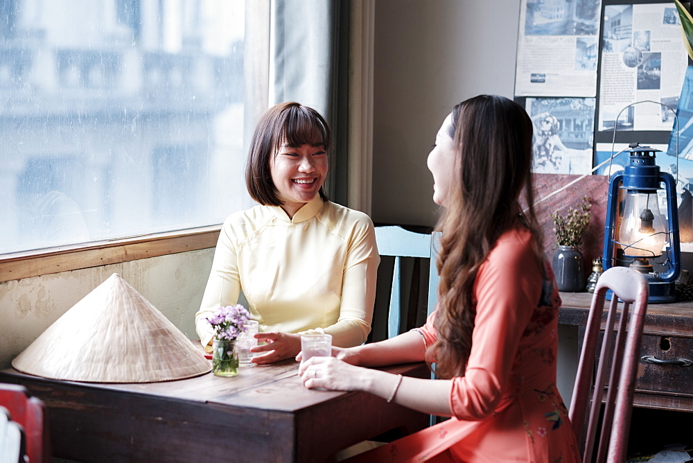 Two friends in Ao Dai dresses taking coffee in a Saigon coffee house, Ho Chi Minh City, Vietnam, Indochina, Southeast Asia, Asia