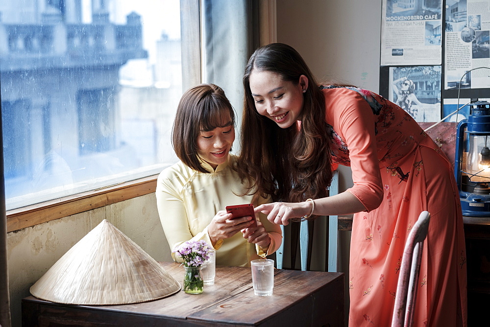 Two friends in Ao Dai dresses taking coffee in a Saigon coffee house, Ho Chi Minh City, Vietnam, Indochina, Southeast Asia, Asia