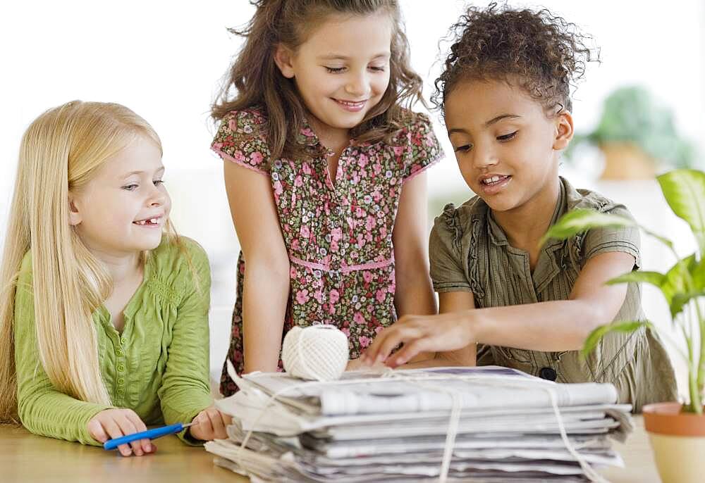 Multi-ethnic girls bundling newspapers