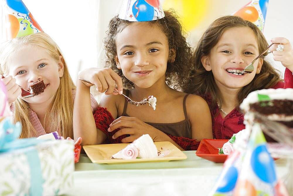 Multi-ethnic girls eating birthday cake