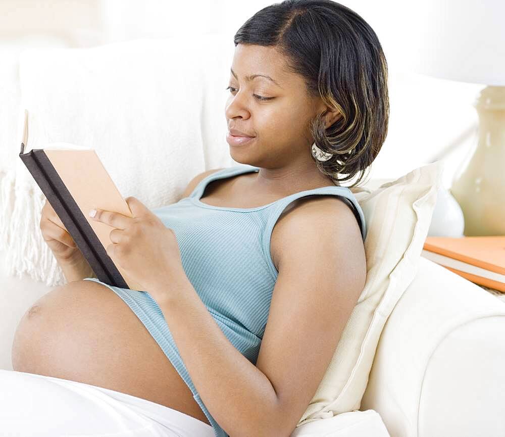 Pregnant African American woman reading book