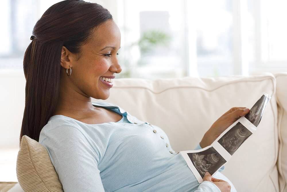 Pregnant African woman looking at ultrasound printout