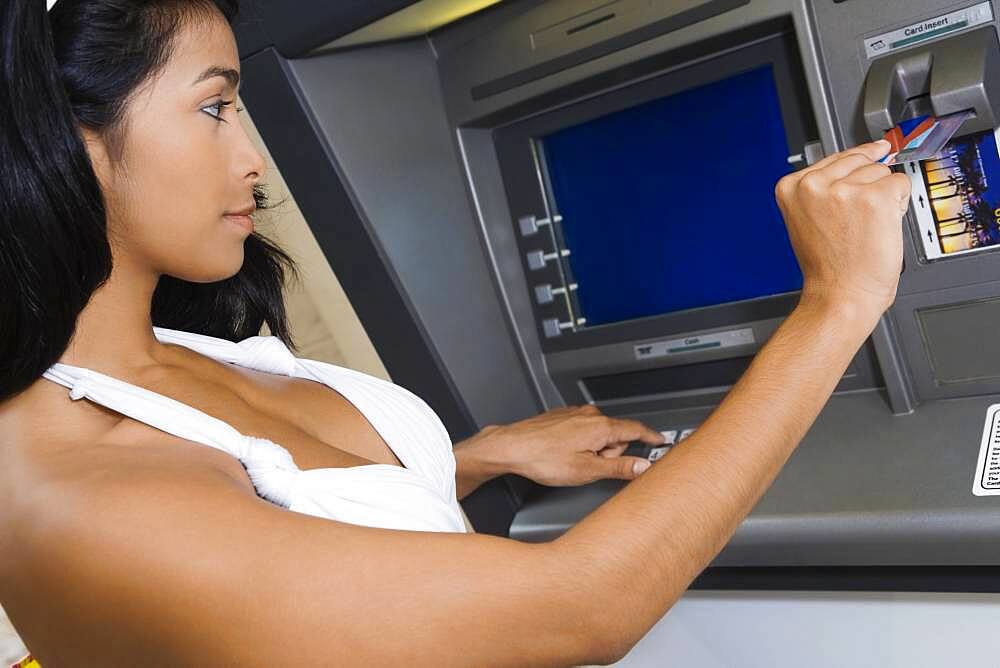 Hispanic woman using atm