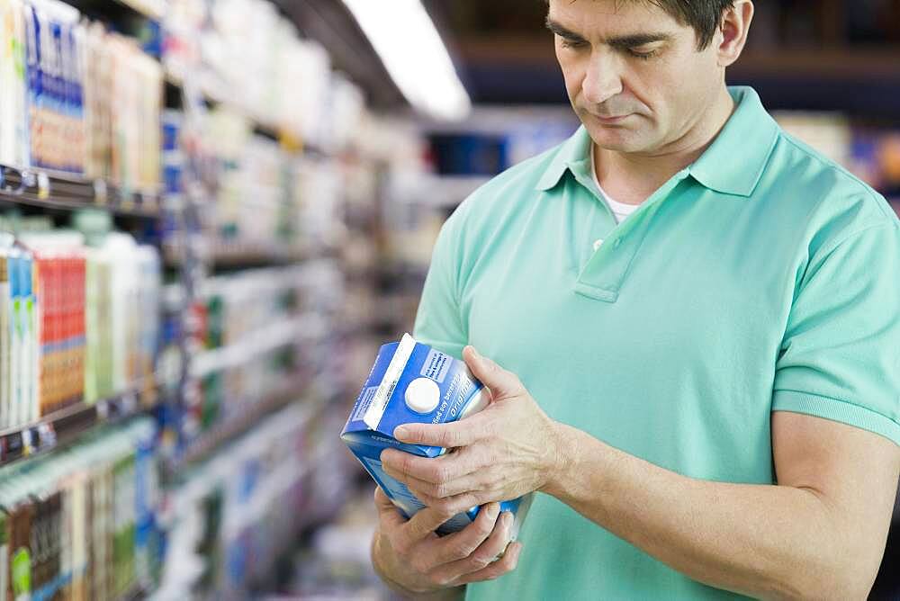 Man reading milk label in grocery store