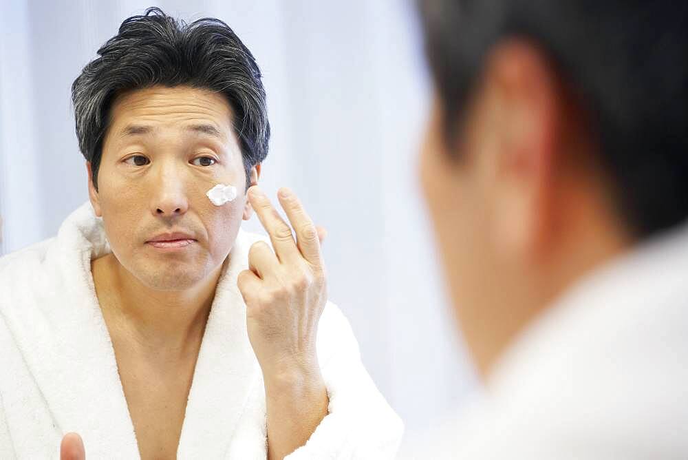 Asian man applying face cream