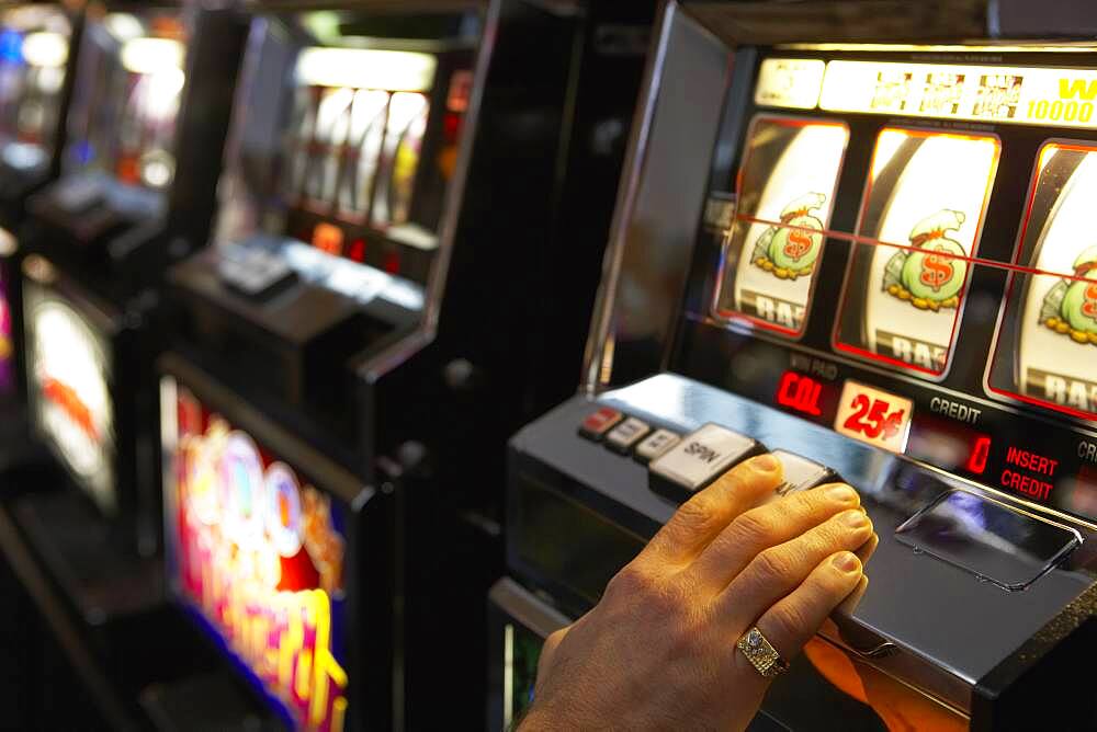 Man pushing the spin button on a slot machine