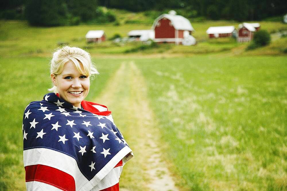 Woman on farm wrapped in American flag