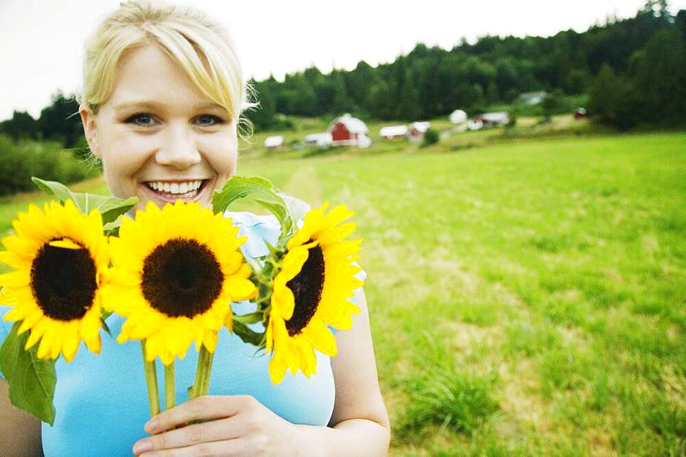 Woman holding sunflowers on farm