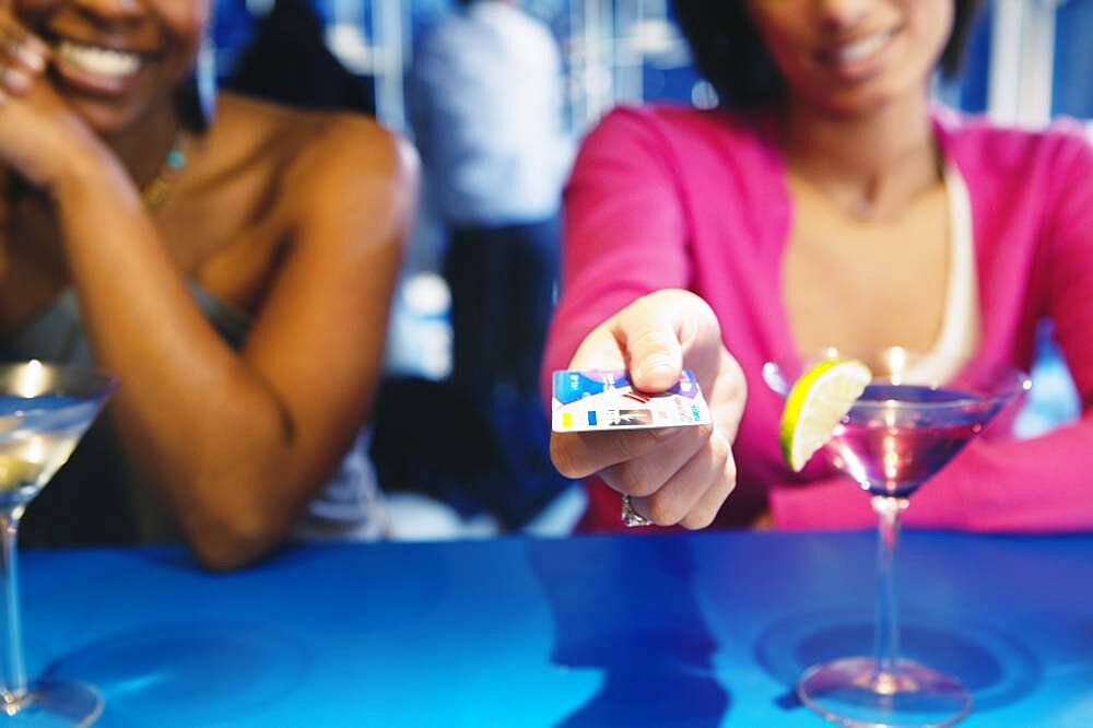 African woman handing credit card over bar