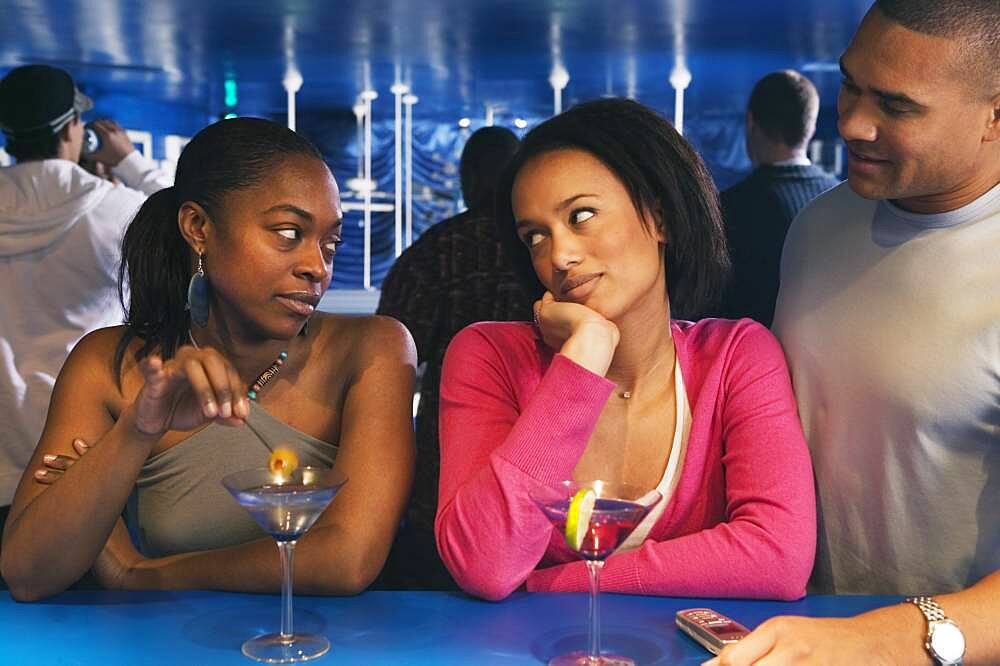 Two African women looking at each other at bar