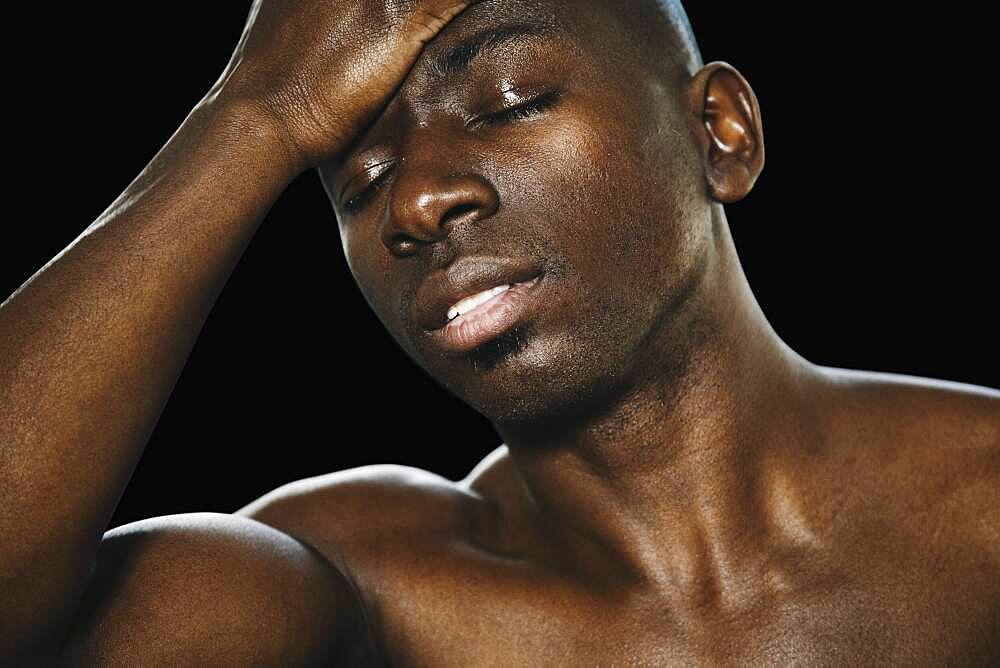 Close up of African man with hand on forehead