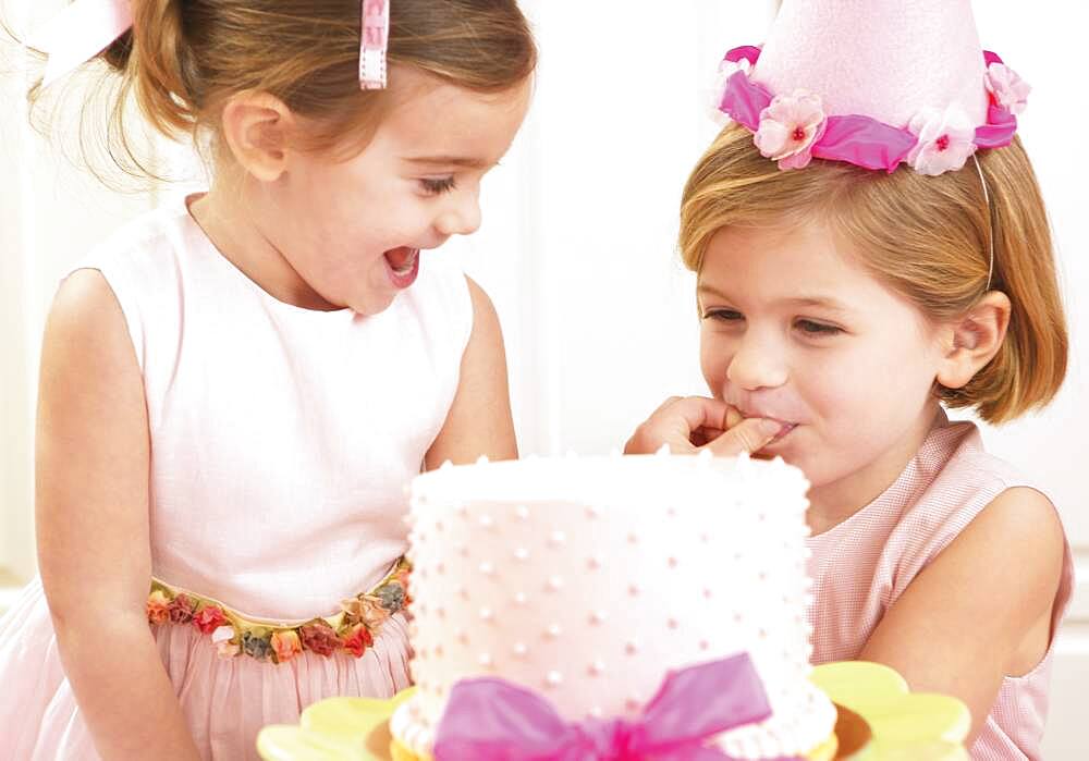 Young girls picking at a birthday cake