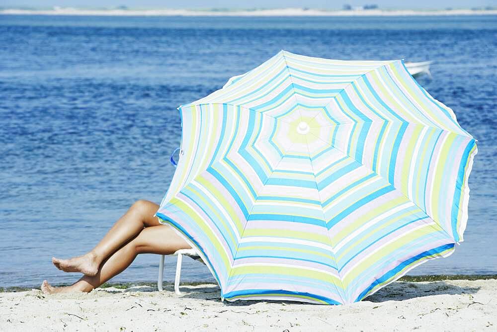 Woman sitting under beach umbrella