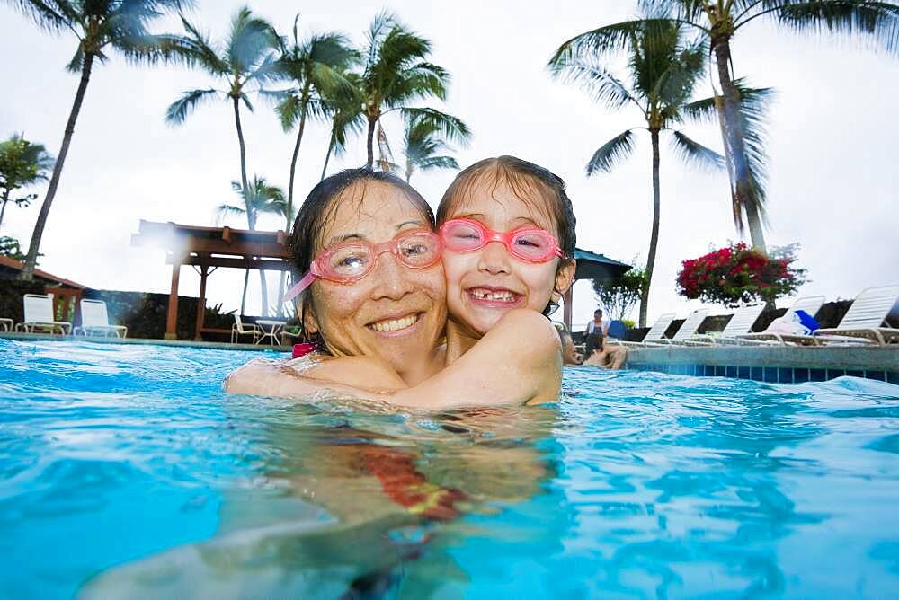 Asian mother and daughter hugging in swimming pool