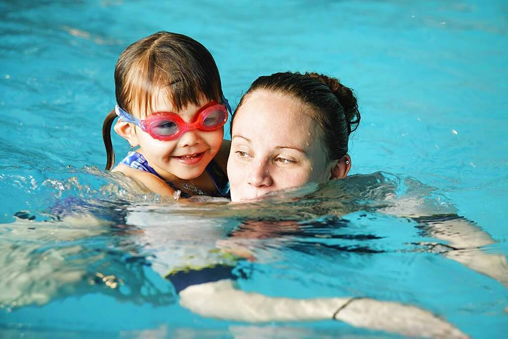 Mother and young daughter swimming