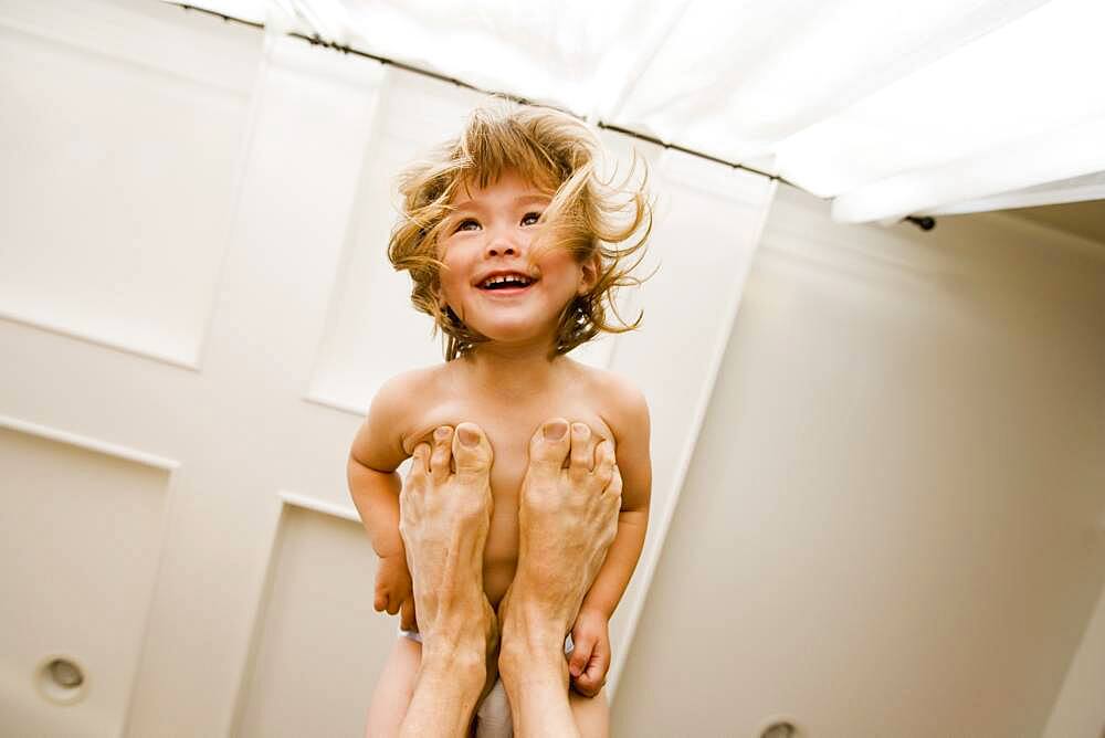 Portrait of girl balanced on father's feet