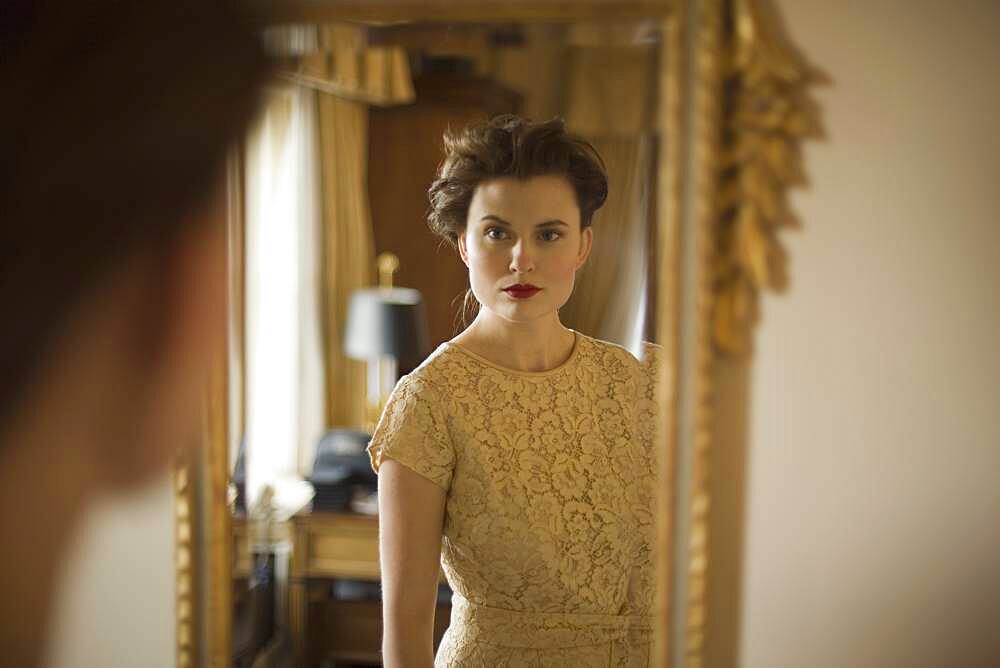 Woman wearing fancy dress looking in mirror