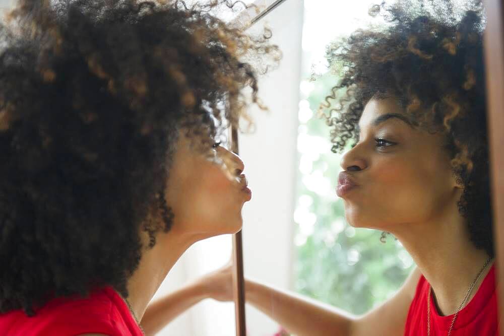 Mixed race woman puckering in mirror