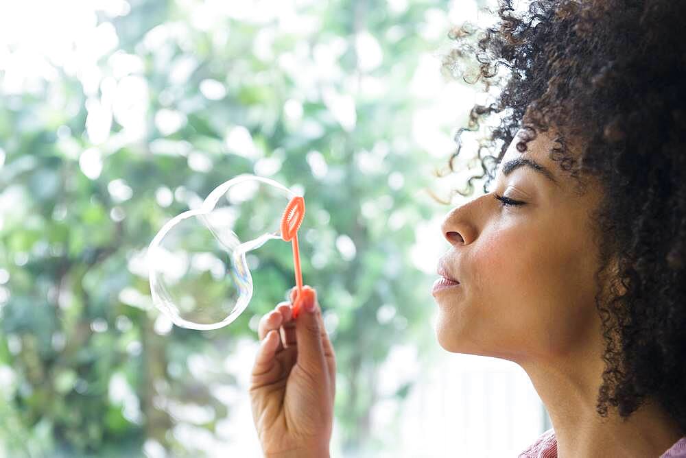 Mixed race woman blowing bubbles