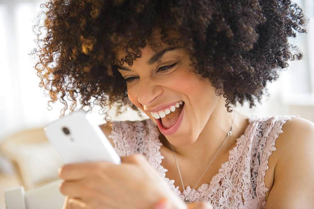 Smiling mixed race woman using cell phone