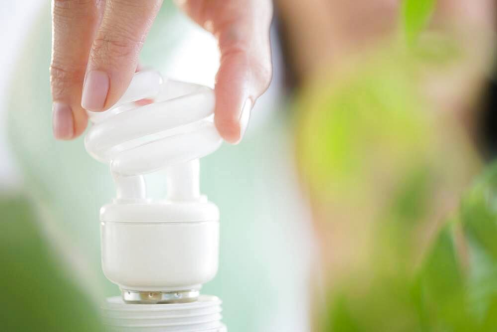 Mixed race woman holding fluorescent light bulb