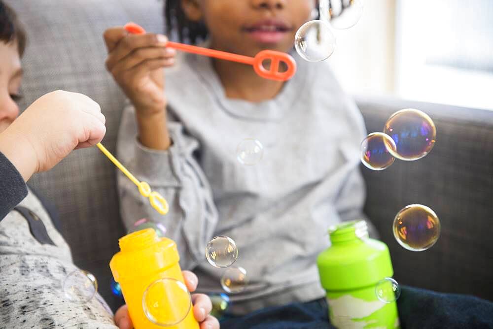 Close up of boys blowing bubbles on sofa