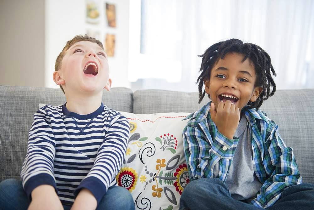 Boys laughing on living room sofa