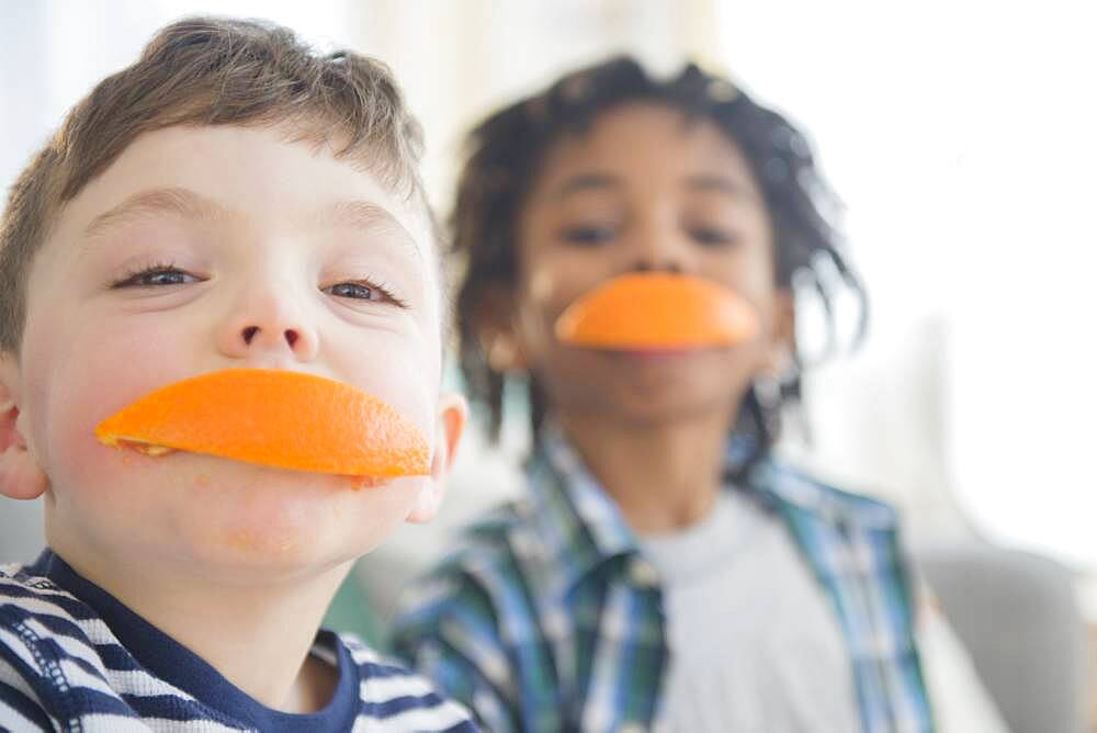 Boys biting orange slices