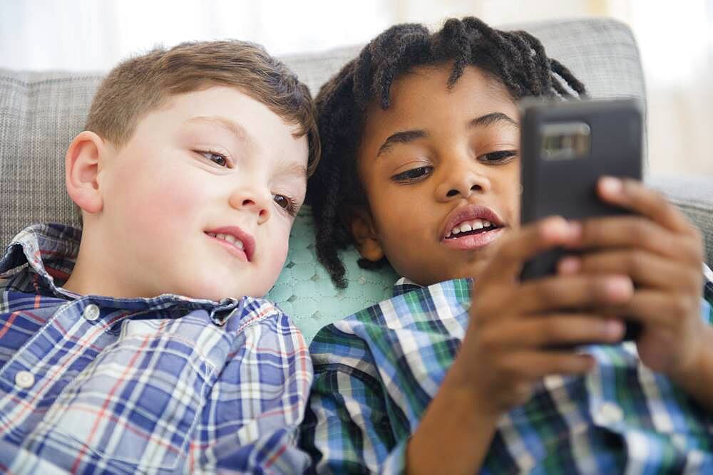 Boys using cell phone on sofa