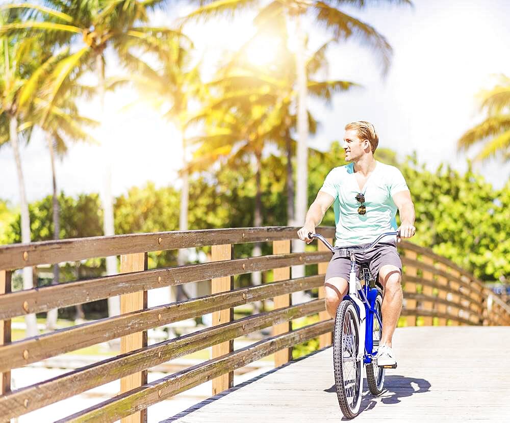 Caucasian man riding bicycle on bridge