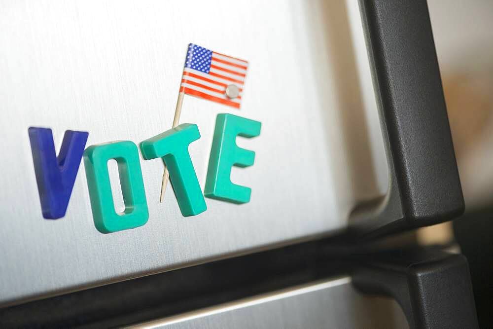 Close up of vote magnets and American flag on refrigerator