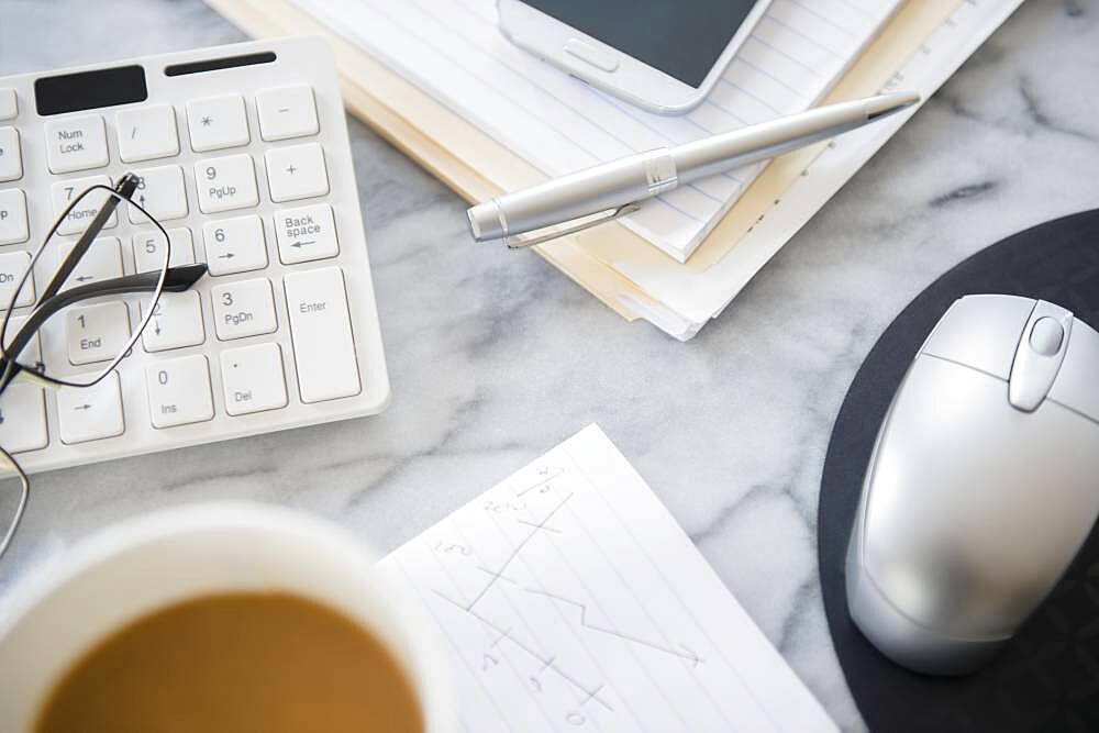 Close up of computer equipment, files and coffee on office desk