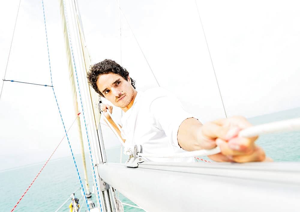 Hispanic man adjusting rigging on sailboat