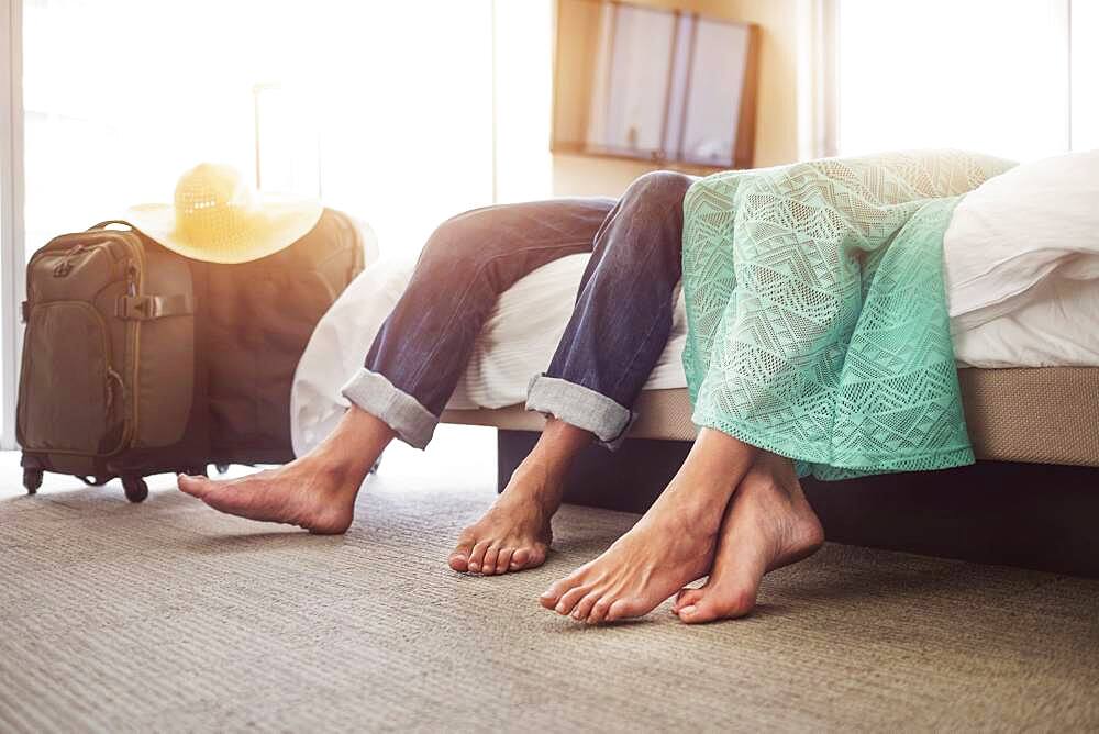 Legs of couple laying on bed in hotel room