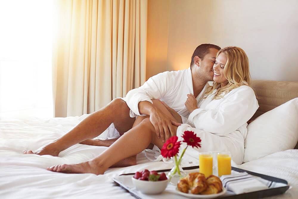 Couple enjoying breakfast in bed in hotel room