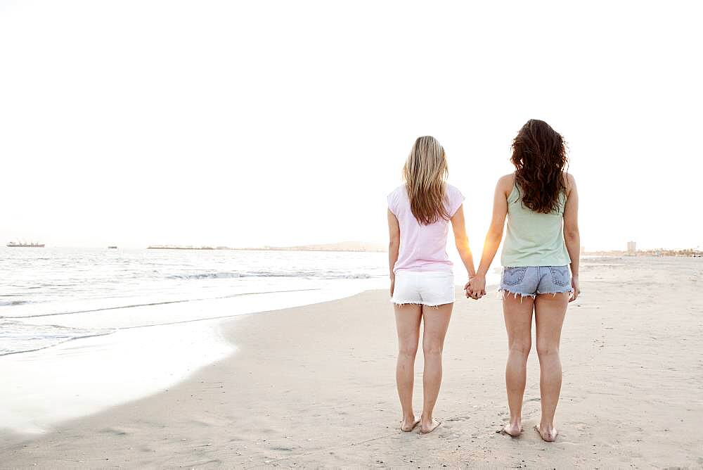 Women holding hands on beach