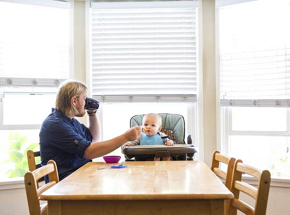 Caucasian father feeding son in high chair