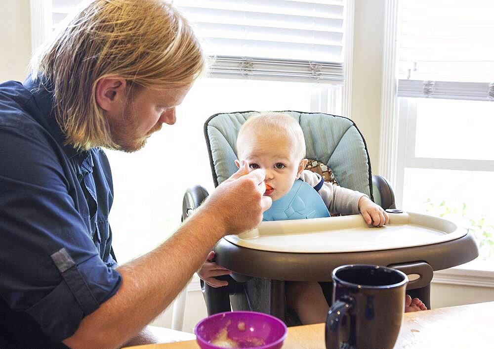 Caucasian father feeding son in high chair