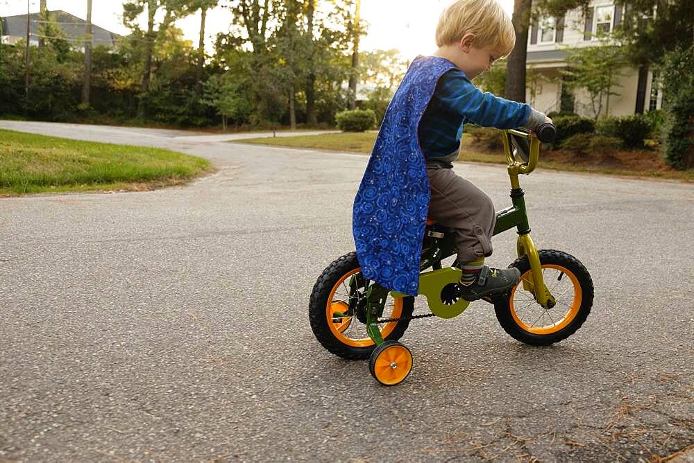 Caucasian boy riding bicycle with training wheels