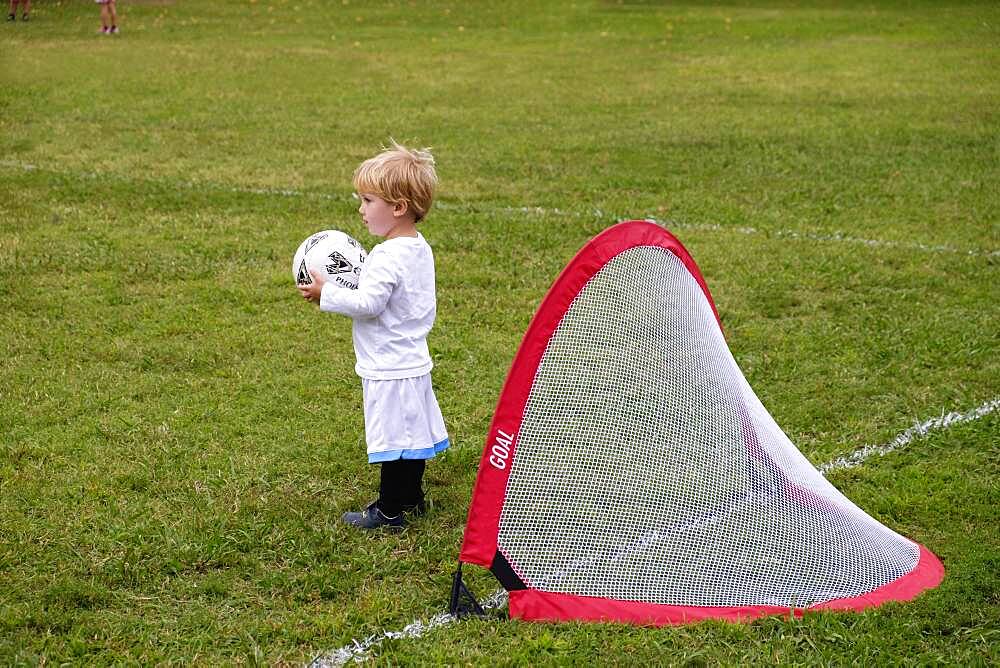 Caucasian boy playing soccer in field